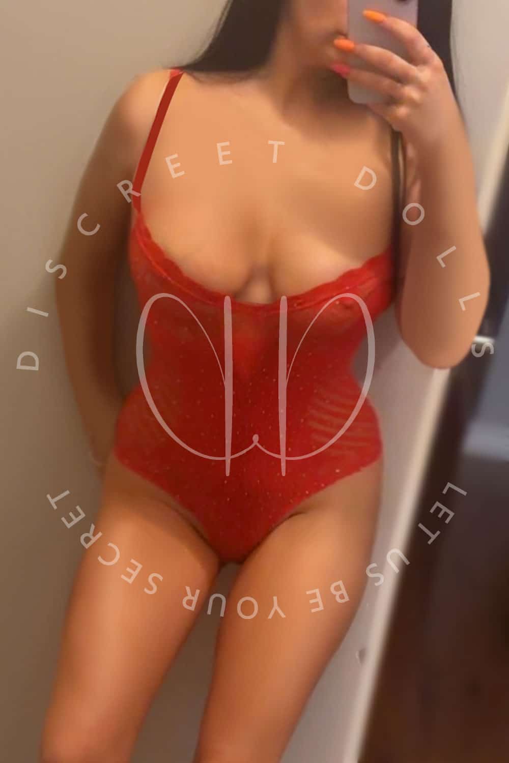 Woman in red lingerie posing for a mirror selfie, phone covering part of her face, with a circular logo/text overlay on the image.