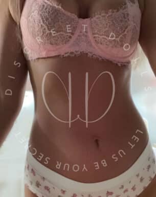 Woman wearing a pink lace bra and white floral underwear, front torso shot for lingerie product display